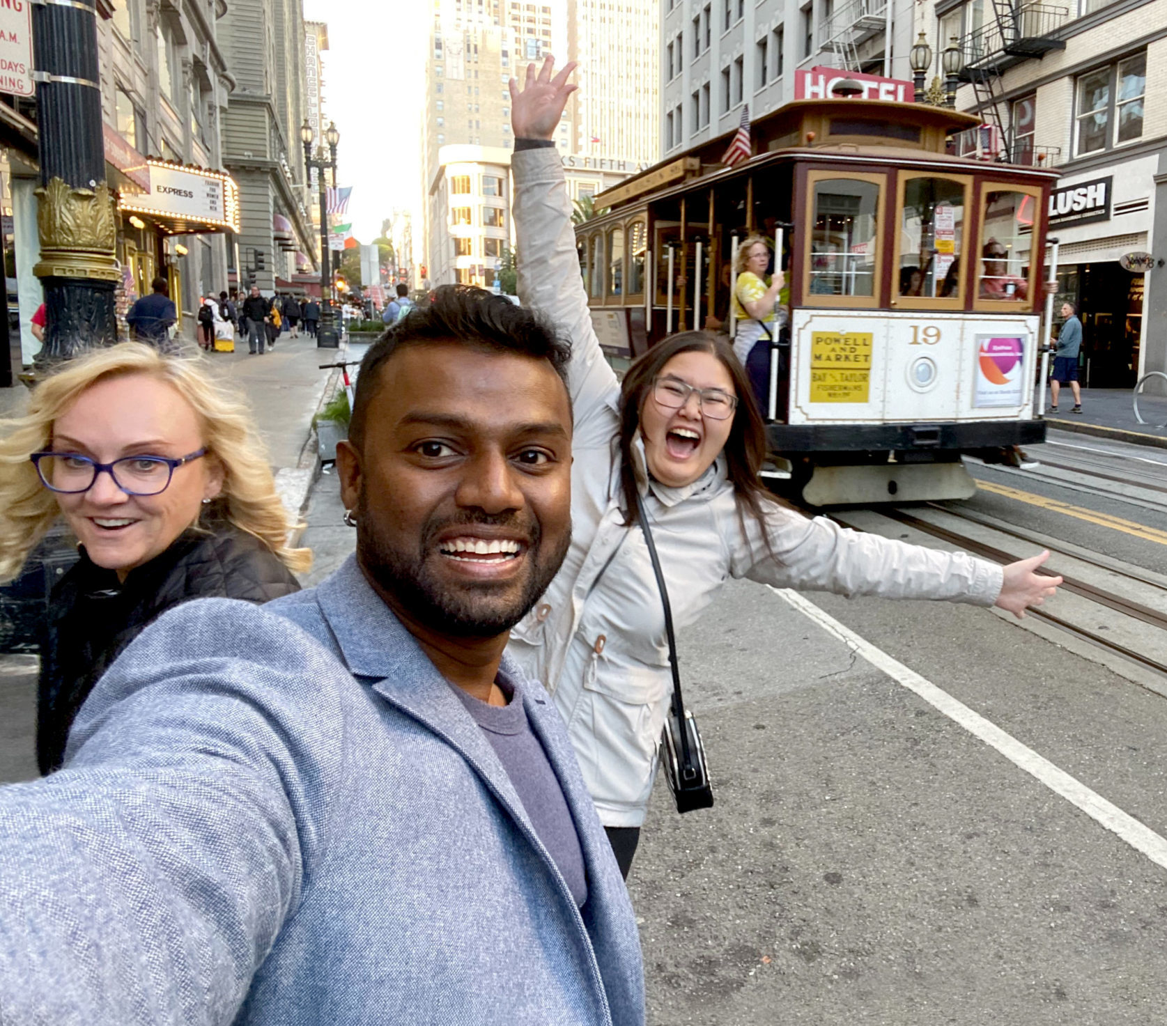 Selfie of PathFactory employees Helen, Murali and Rachel smiling on a street in San Francisco with the famous trolley cars in the background